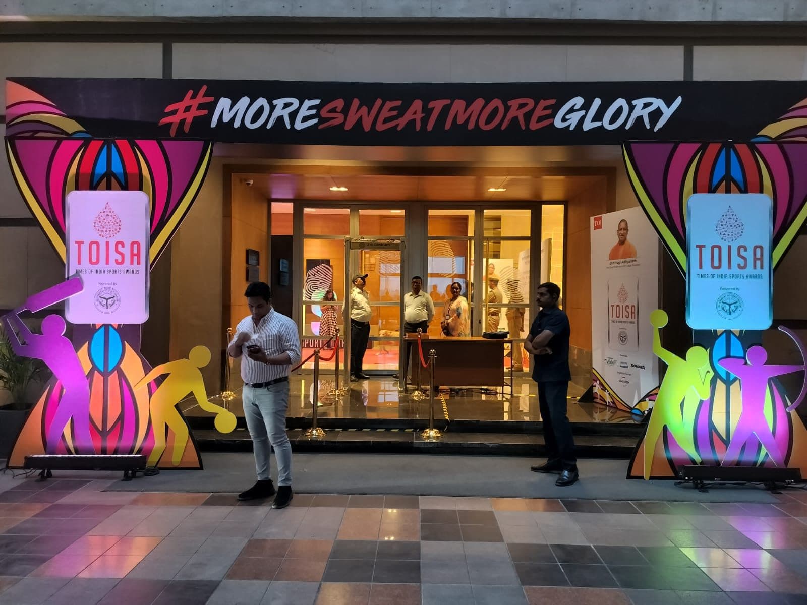 Colorful TOISA activation entrance with sports-figure murals and #MoreSweatMoreGlory signage