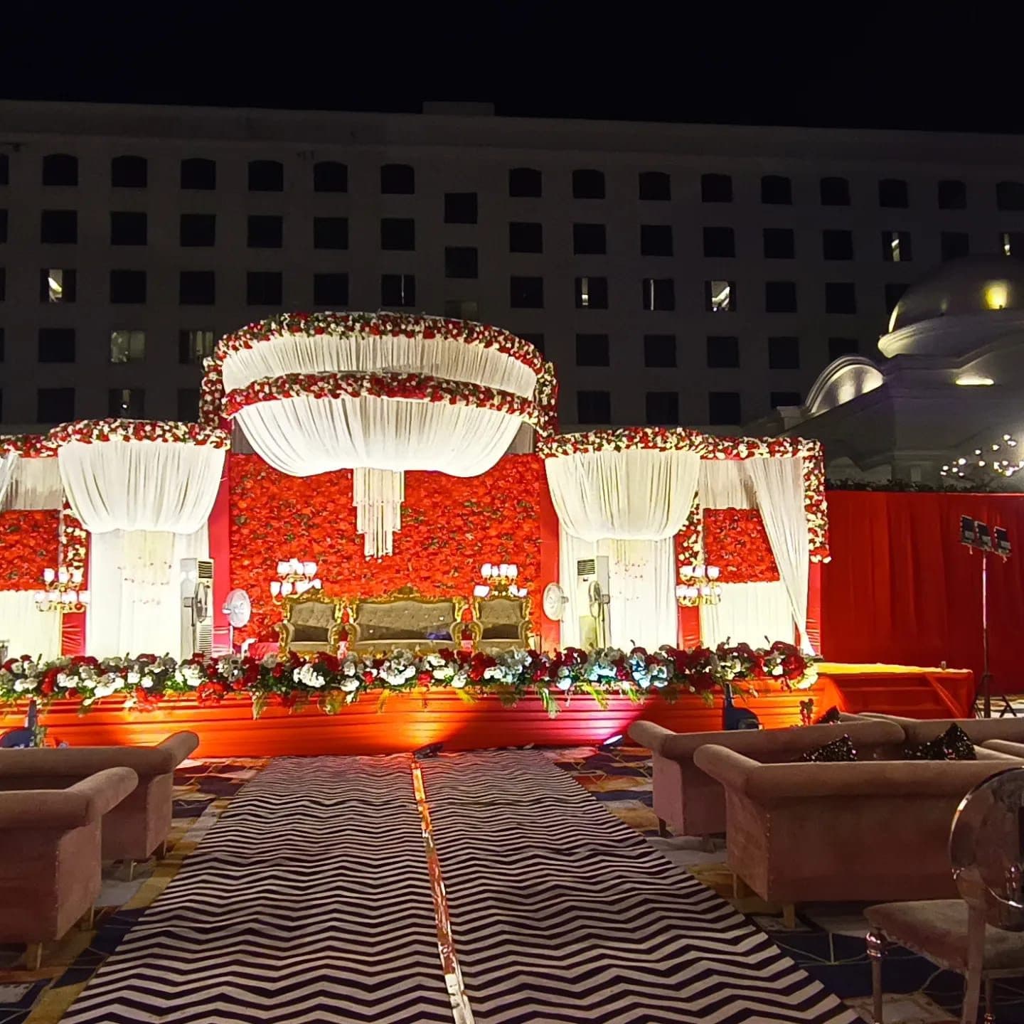 Wedding reception stage with red and white floral drapery