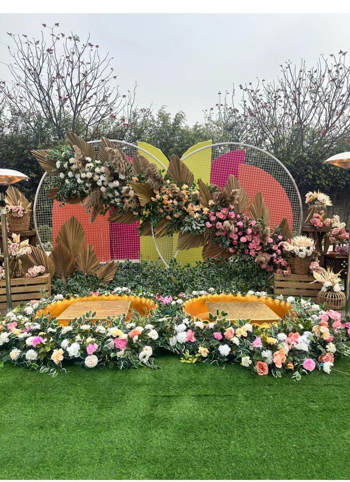 Outdoor haldi ceremony seating with boho floral ring backdrop